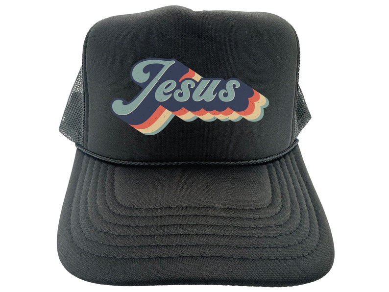 Puede incluir: Gorra de camionero negra con un gr&aacute;fico retro de "Jes&uacute;s" en azul, rojo y blanco.