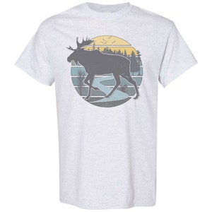 May include: A gray t-shirt with a vintage-style graphic of a moose walking through a forest with a sunset in the background.