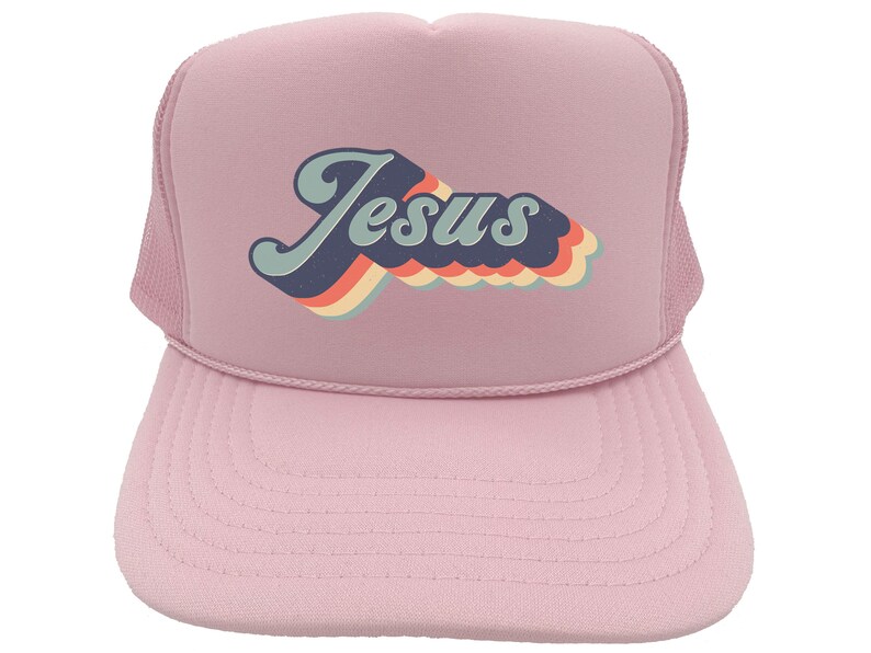 Puede incluir: Gorra de camionero rosa con un gr&aacute;fico retro de "Jes&uacute;s" en colores arco&iacute;ris.