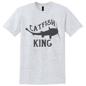 May include: A heather grey t-shirt with a black silhouette of a catfish and the text "CATFISH KING" printed on the front.