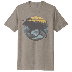 May include: A heather grey t-shirt with a vintage-style graphic of a moose walking through a forest with a river and a sunset in the background.