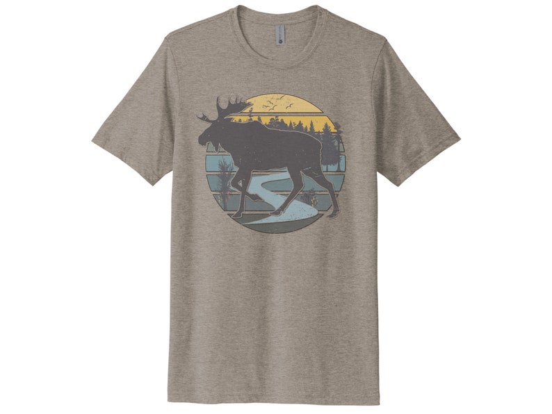 May include: A heather grey t-shirt with a vintage-style graphic of a moose walking through a forest with a river and a sunset in the background.