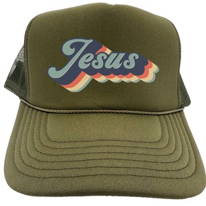 Puede incluir: Una gorra de camionero verde con un gr&aacute;fico retro de "Jes&uacute;s" en azul, rojo, naranja y amarillo.