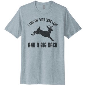 May include: A light blue t-shirt with a black silhouette of a deer with large antlers and the text "I like 'em with long legs and a big rack".