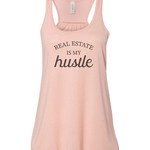 May include: A peach-colored tank top with the text "REAL ESTATE IS MY hustle" printed in brown.