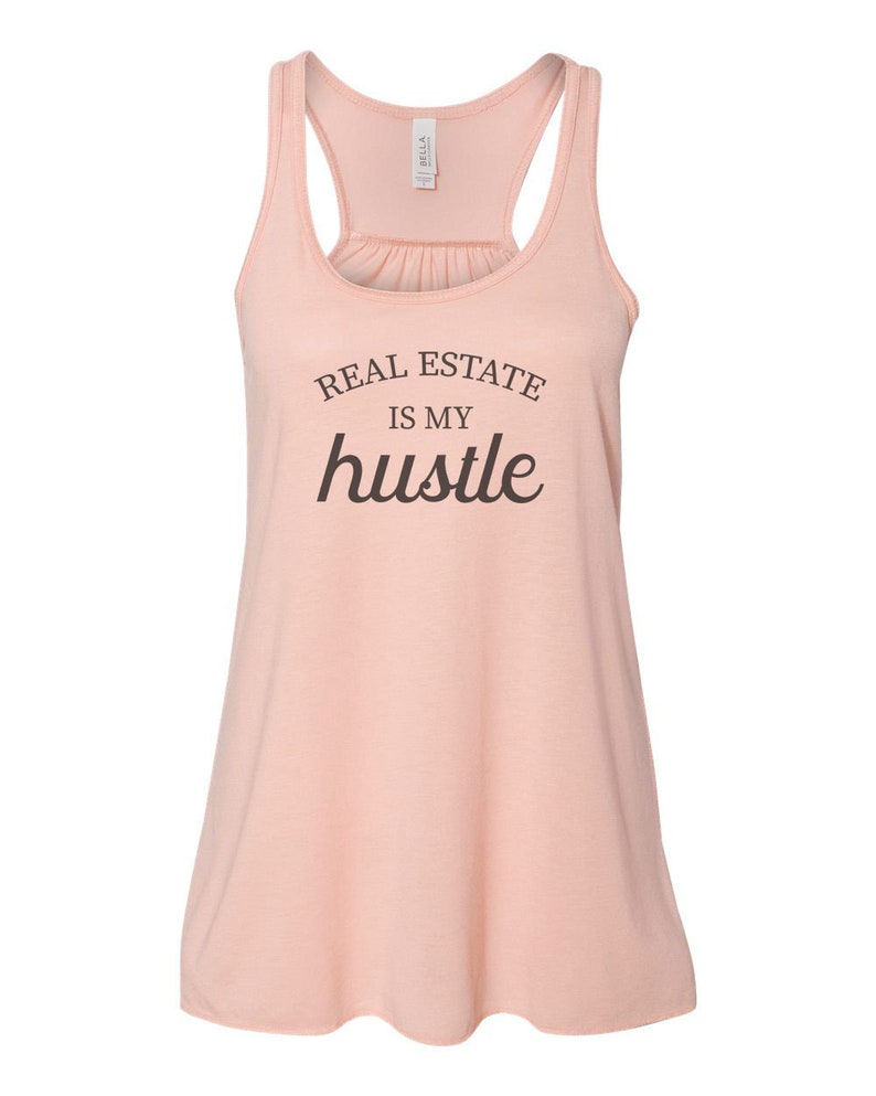 May include: A peach-colored tank top with the text "REAL ESTATE IS MY hustle" printed in brown.