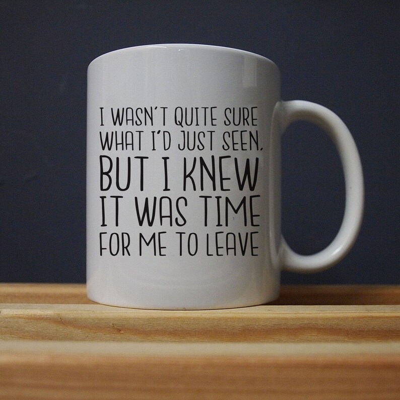 Pu&ograve; includere: Tazza in ceramica bianca con manico nero. La tazza presenta il testo: "I WASN'T QUITE SURE WHAT I'D JUST SEEN, BUT I KNEW IT WAS TIME FOR ME TO LEAVE." La tazza &egrave; su una superficie di legno.