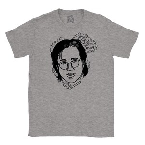 May include: A grey t-shirt featuring a black and white illustration of a person wearing glasses and holding a cigarette. The text "Well, looks like we got ourselves a reader?" is in a speech bubble above the person's head.