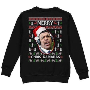 Peut inclure: Pull de Noël noir avec un motif rouge et blanc. Le pull présente une photo de Chris Kamara portant un bonnet de Père Noël et un microphone. Le texte "Merry Chris Kamaras" est imprimé sur le pull.