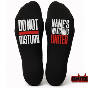 May include: Pair of black insoles with the phrases "DO NOT DISTURB" and "NAME'S WATCHING UNITED" in white text. The word "UNITED" is in red. A small "UNITED" keychain is also included.