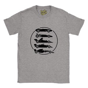 Op de afbeelding: Grijze t-shirt met een zwarte afbeelding van vijf raceauto's in een zwarte cirkel. Het shirt heeft een ronde hals en korte mouwen. De merknaam "Howlin Lemon" staat rechtsboven gedrukt.