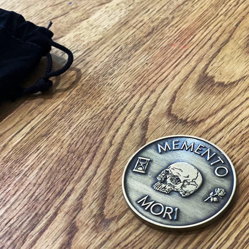 May include: A gold-toned metal coin with the words "Memento Mori" and an hourglass, skull, and rose design.
