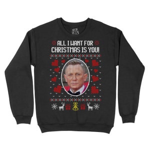 May include: Black Christmas jumper with a red and white pattern. The jumper features a picture of a man with a black bow tie and the text "All I want for Christmas is you!"