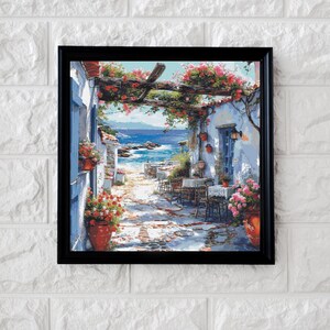 Puede incluir: Una pintura de un edificio blanco con una puerta azul y un patio con mesas y sillas. El edificio está cubierto de enredaderas y flores. El patio tiene vistas a un océano azul.