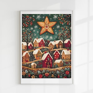 Op de afbeelding: Een ingelijste prent met een grillige kerstdorp-scène. Het kunstwerk toont met sneeuw bedekte huizen in tinten rood, goud en bruin, genesteld op een heuvel onder een grote ster en een donkergroene lucht met sneeuwvlokken.