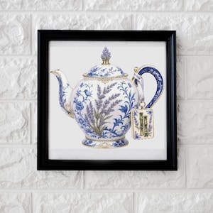 May include: A white ceramic teapot featuring a blue floral and lavender sprig pattern, housed in a black square frame. The teapot has a matching lid with a finial, a curved handle, and a rectangular tag hanging from the handle with green bamboo.