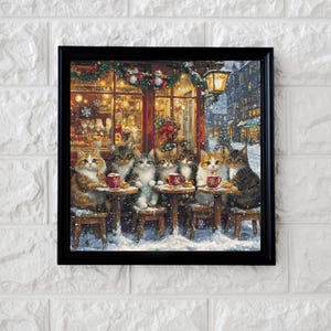 May include: A framed print depicts a cozy winter scene with several cats gathered at small tables outside a cafe. The cats, with various fur patterns, are enjoying drinks. The cafe is decorated with festive lights and garlands, and snow falls gently.