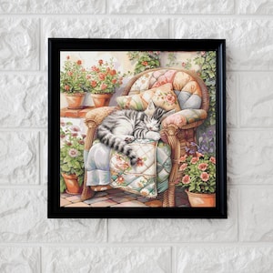 Könnte beinhalten: Ein gerahmter Aquarelldruck zeigt eine grau-weiße Tabby-Katze, die friedlich auf einem Korbstuhl schläft. Der Stuhl ist mit floralen Kissen und einer gesteppten Decke geschmückt. Topfpflanzen und Grün umgeben den Stuhl und schaffen eine gemütliche Szene.