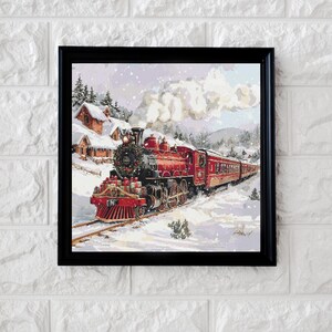 May include: A red and black train engine pulls a string of passenger cars through a snowy winter landscape. The train is decorated with greenery and presents, suggesting a holiday theme.