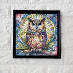 Könnte beinhalten: Gerahmtes Kunstwerk mit einer farbenfrohen Eulenillustration. Die Eule sitzt auf einem Ast, mit einem Hintergrund im Buntglasstil in Blau-, Gelb- und Rosatönen. Das Kunstwerk ist in einem schwarzen Rahmen eingefasst, geeignet für Wanddekoration.