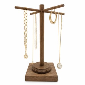 May include: A wooden jewelry display stand with a square base and a central post with horizontal arms. Gold necklaces, a pearl necklace, and gold hoop earrings hang from the arms. A gold necklace with a sun pendant and a gold necklace with a white pendant are also displayed.