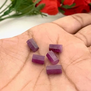 以下が含まれることがあります： 手のひらに、長方形の形状をした紫色の宝石ビーズが5つ置かれています。ビーズは滑らかで、わずかに光沢があります。