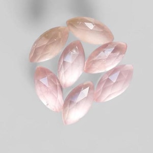 May include: A group of seven pink rose quartz gemstones, each cut into a marquise shape with a faceted finish.