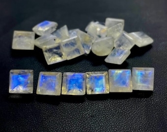 Könnte beinhalten: Eine Gruppe von irisierenden weißen Mondstein-Quadratcabochons, einige sind lose und andere sind in einer Reihe angeordnet.