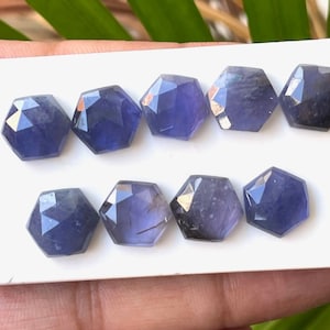 Peut inclure: Huit cabochons de pierres précieuses violettes facettées, chacun de forme hexagonale, disposés en deux rangées sur un fond blanc.