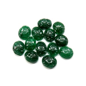 May include: A group of 14 green oval cabochon gemstones with a carved floral design. The gemstones are arranged in a loose pile on a white background.