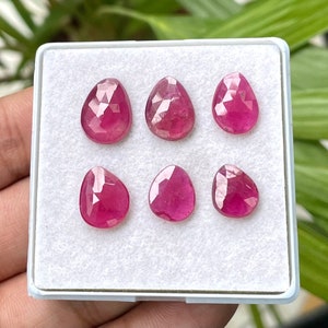 May include: Six pink gemstone drops in a white box. The gemstones are faceted and have a pear shape.