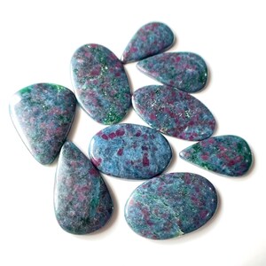 Pode incluir: Uma coleção de dez cabochões de zoisita rubi azul, verde e rosa. As pedras são de várias formas e tamanhos, com um padrão salpicado.