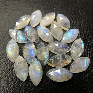 May include: A collection of 17 marquise-shaped moonstone gemstones. The stones are a milky white colour with iridescent blue and green flashes.