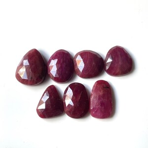 Pu&ograve; includere: Sette pietre preziose di rubino sfaccettate di varie forme e dimensioni. Le pietre preziose sono di colore rosso intenso e hanno una finitura lucida.