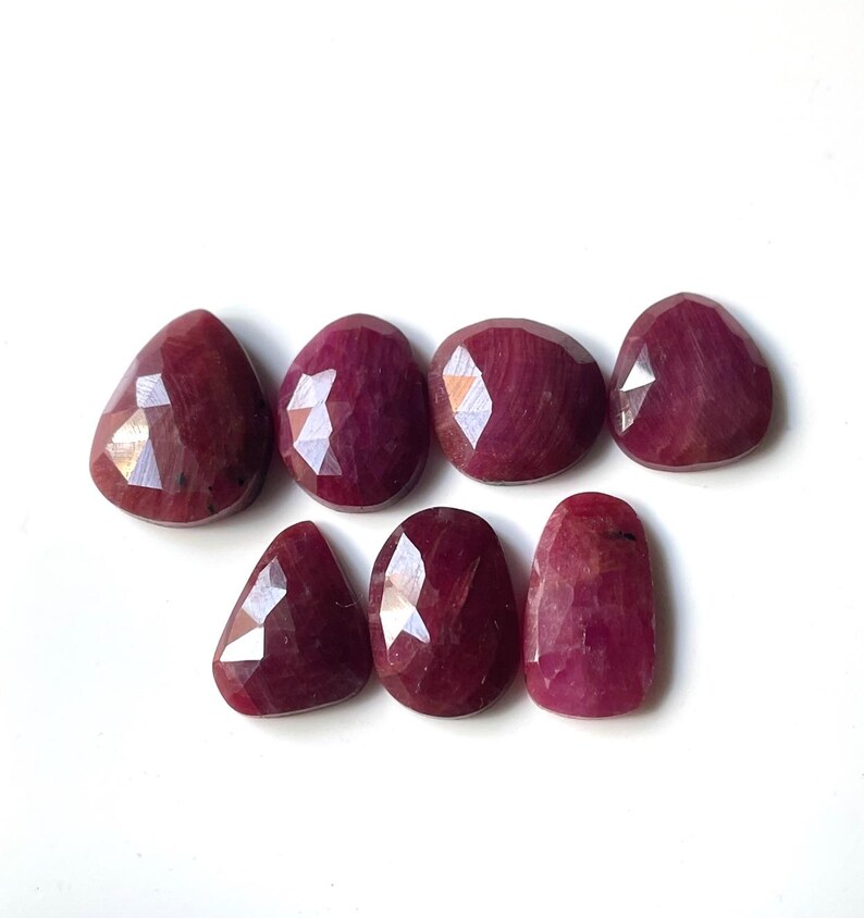Pu&ograve; includere: Sette pietre preziose di rubino sfaccettate di varie forme e dimensioni. Le pietre preziose sono di colore rosso intenso e hanno una finitura lucida.
