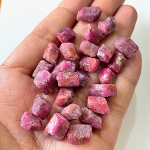 以下が含まれることがあります： さまざまなサイズと形のピンクのルビーの原石の集まり。結晶は未加工で、自然な研磨されていない仕上げになっています。