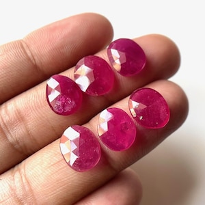May include: Six faceted ruby gemstones in a variety of sizes and shapes. The gemstones are a deep red color and have a glossy finish.