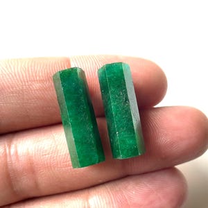 Op de afbeelding: Twee smaragdgroene edelsteen cabochons, gesneden in rechthoekige vormen met gefacetteerde randen. De cabochons zijn ongeveer 2,5 cm lang en 1,25 cm breed.