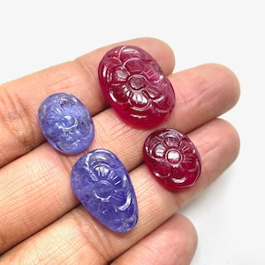 May include: Four carved gemstone cabochons, two red and two blue. The red cabochons are carved with a flower design and the blue cabochons are carved with a flower and leaf design.