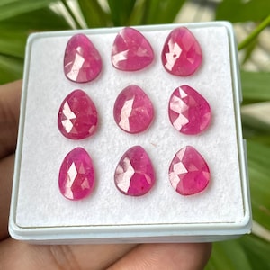 Peut inclure: Une collection de huit pierres précieuses de rubis facettées dans une boîte blanche. Les rubis sont de couleur rose foncé et ont une forme de larme.