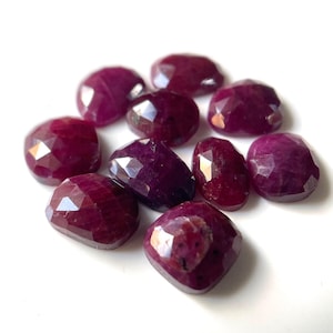 May include: Ten faceted ruby gemstones in a variety of sizes and shapes. The gemstones are a deep red color and have a polished finish.