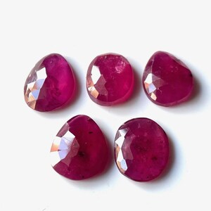 Puede incluir: Cinco piedras preciosas de rubí facetadas en forma de lágrima. Las piedras preciosas son de color rojo intenso y tienen un acabado pulido.