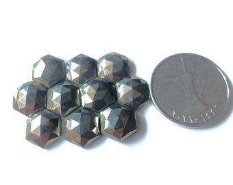 May include: A collection of faceted, hexagonal pyrite gemstones in shades of gray and silver. A silver coin is next to the gemstones. The gemstones are arranged in a honeycomb pattern, reflecting light.