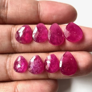 Puede incluir: Ocho piedras preciosas de rubí en forma de pera facetadas de diferentes tamaños. Las piedras preciosas son de color rosa intenso y tienen un acabado brillante.