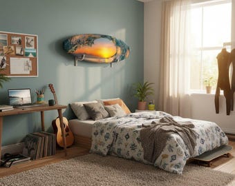 Op de afbeelding: Een slaapkamerinterieur met een surfboardvormige wandkunst die een zonsondergang over de oceaan afbeeldt. De kamer heeft een bed met een patroonbed, een houten bureau met een laptop en een gitaar. Een wetsuit hangt aan de muur.