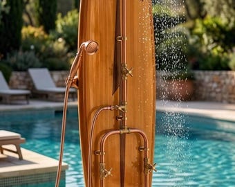 May include: An outdoor shower system mounted on a wooden surfboard with the text HUNTINGTON BEACH. It features copper piping, a round overhead shower head, a handheld shower attachment, two control valves, and a lower faucet.