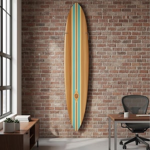 May include: A wooden surfboard with a light brown finish, teal and yellow stripes, and a decorative emblem. The surfboard is mounted on a red brick wall. The surfboard is approximately 7 feet long.