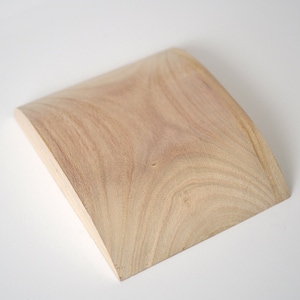 May include: A light brown wooden tray with a curved shape. The tray is made of natural wood and has a smooth surface.