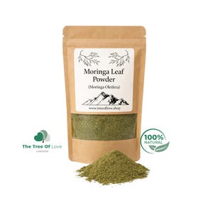 May include: A brown kraft paper pouch containing green Moringa Leaf Powder. The label features the text Moringa Leaf Powder (Moringa Oleifera), a mountain illustration, and the website www.treeoflove.shop. A pile of the green powder sits in front.
