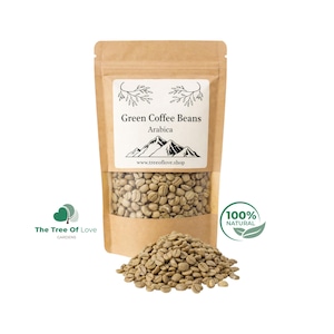 May include: A brown paper pouch filled with raw green Arabica coffee beans. The label features a mountain graphic, the text Green Coffee Beans, Arabica, and www.treeoflove.shop. A pile of the same light green, unroasted coffee beans sits in front.